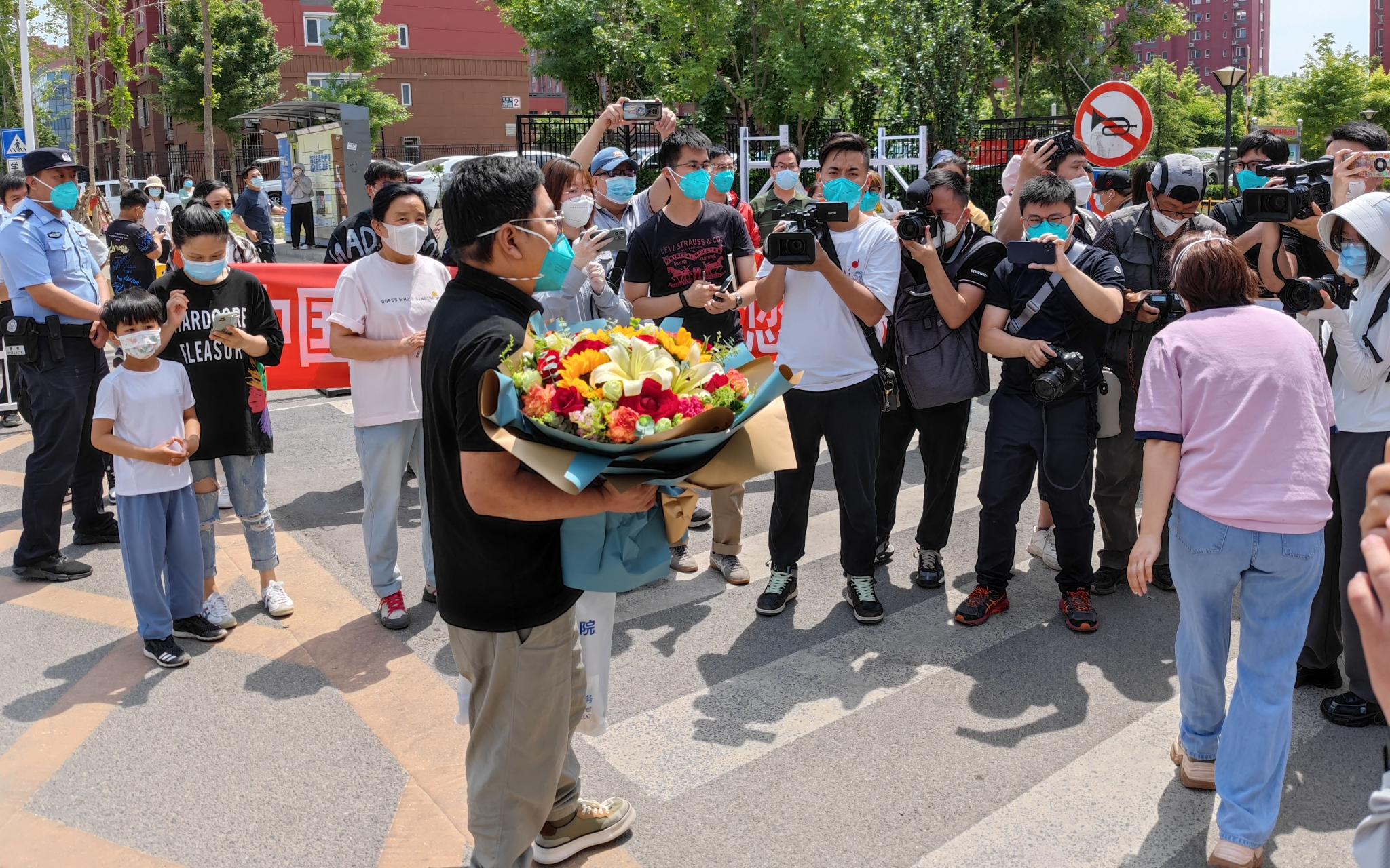 5月18日上午11点,在冠华苑社区门口,邻居们欢迎张旭回家。新京报记者 王巍 摄